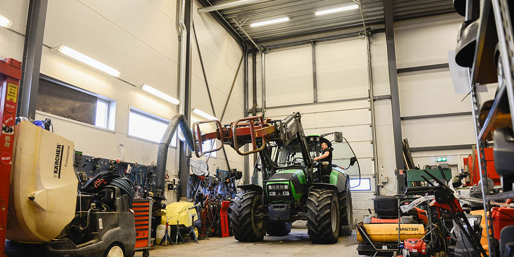 En mann i traktor i verkstedet til Jeka Maskiner