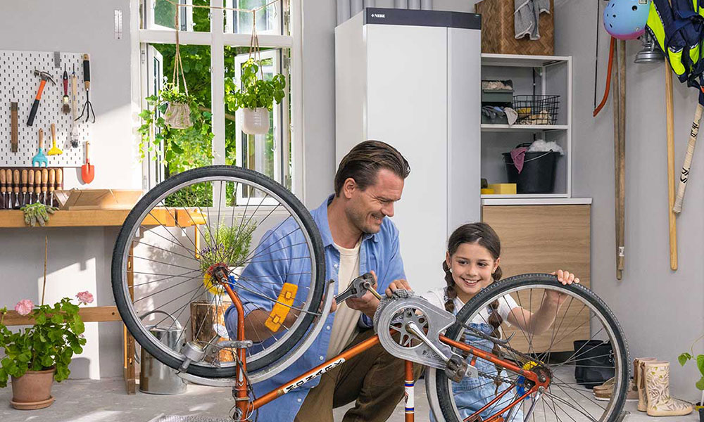 NIBE S1256 i bakgrunnen, og en far og datter som mekker sykkel
