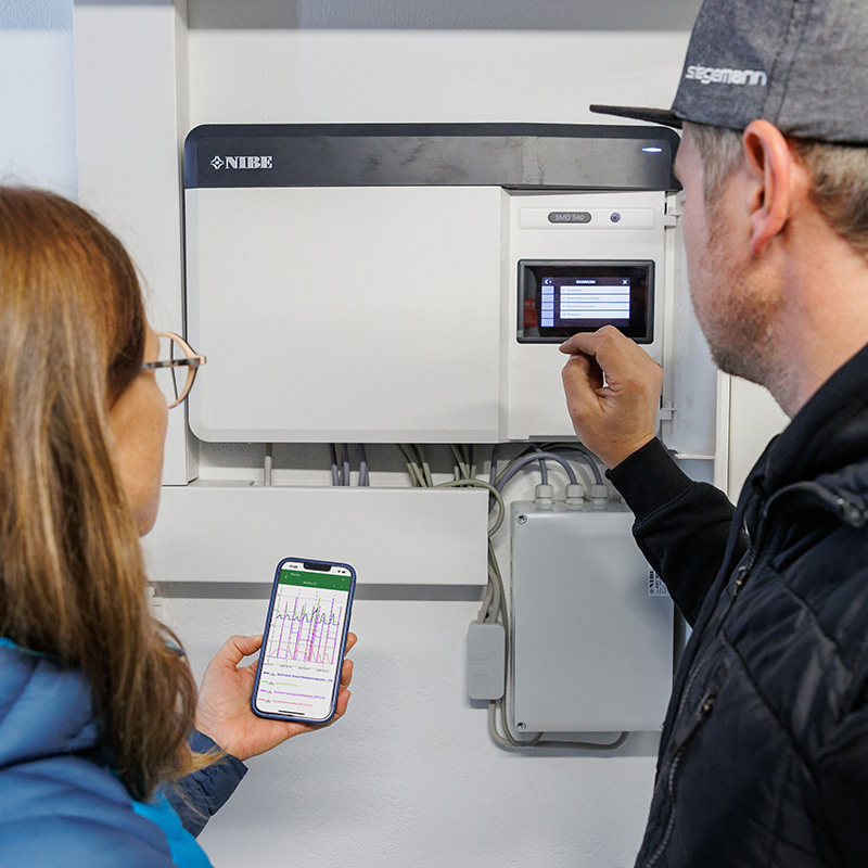 Installateur und Kundin überprüfen die Werte der Wärmepumpe